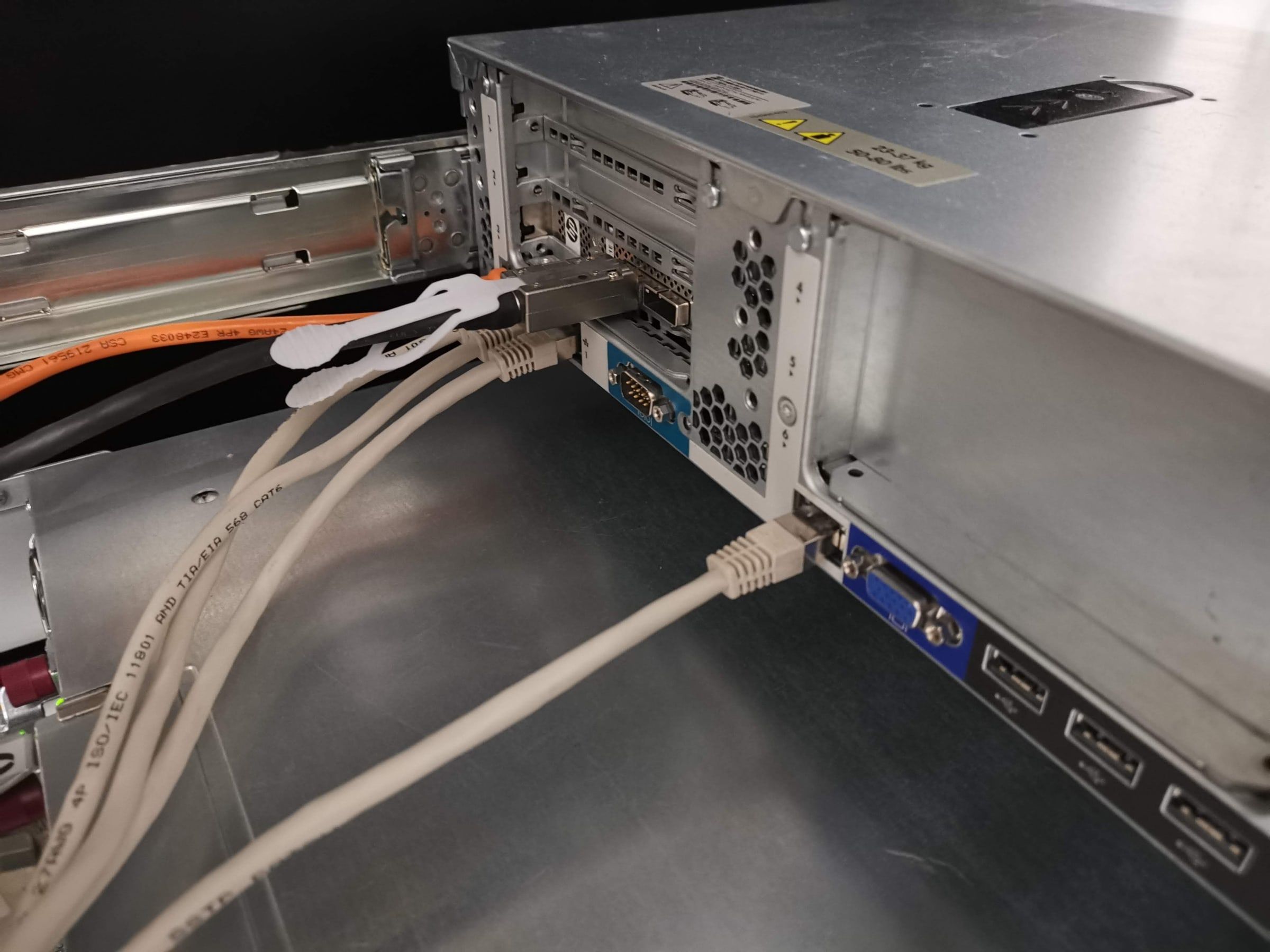 Rückseite eines Serverschranks mit Netzteilen, Stromzuführung und angeschlossenen Netzwerkkabeln.